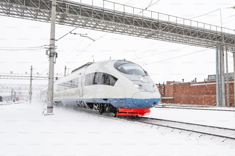 High speed train approaches to the station platform at winter day snowstorm