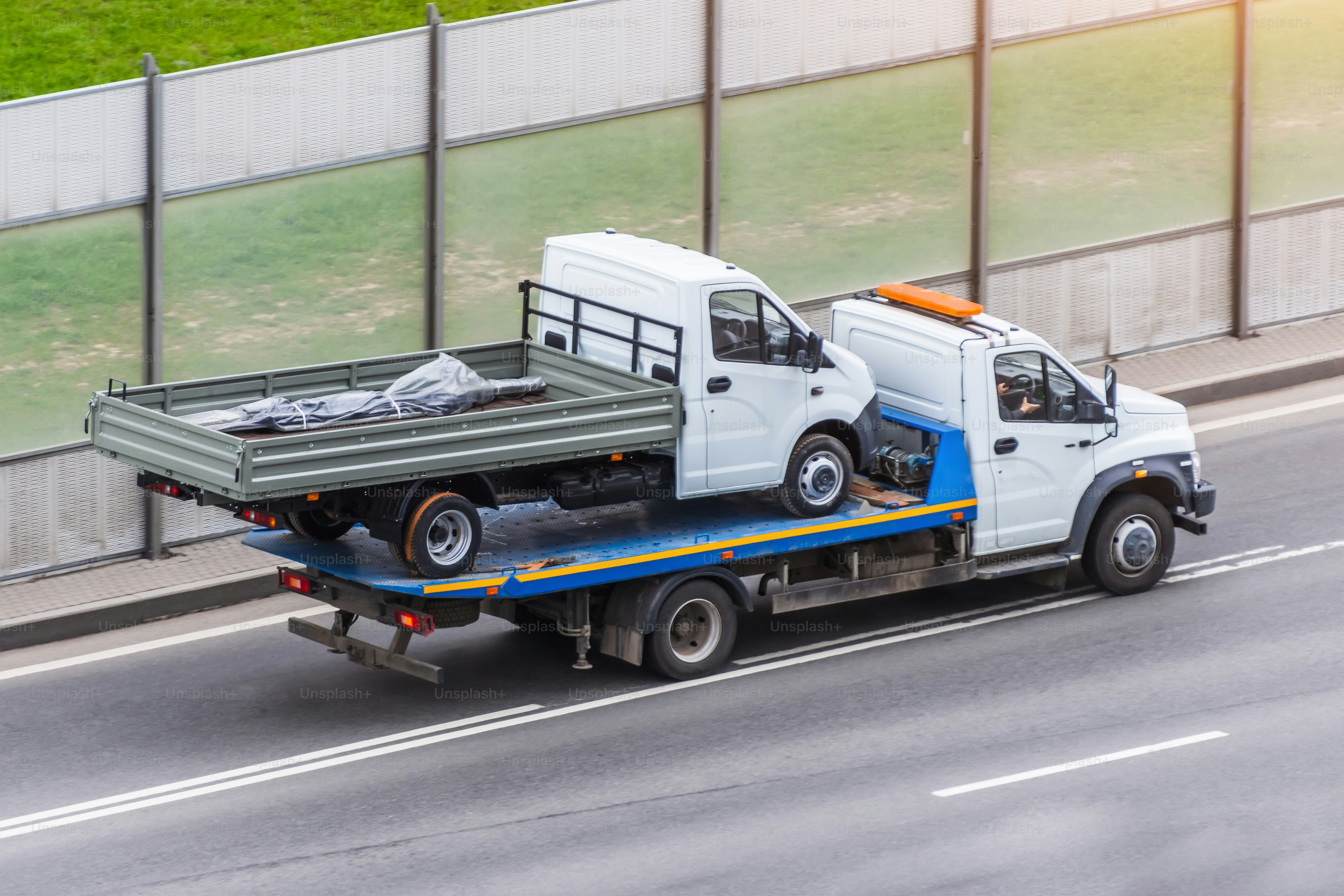 A truck is transporting another small truck on the road