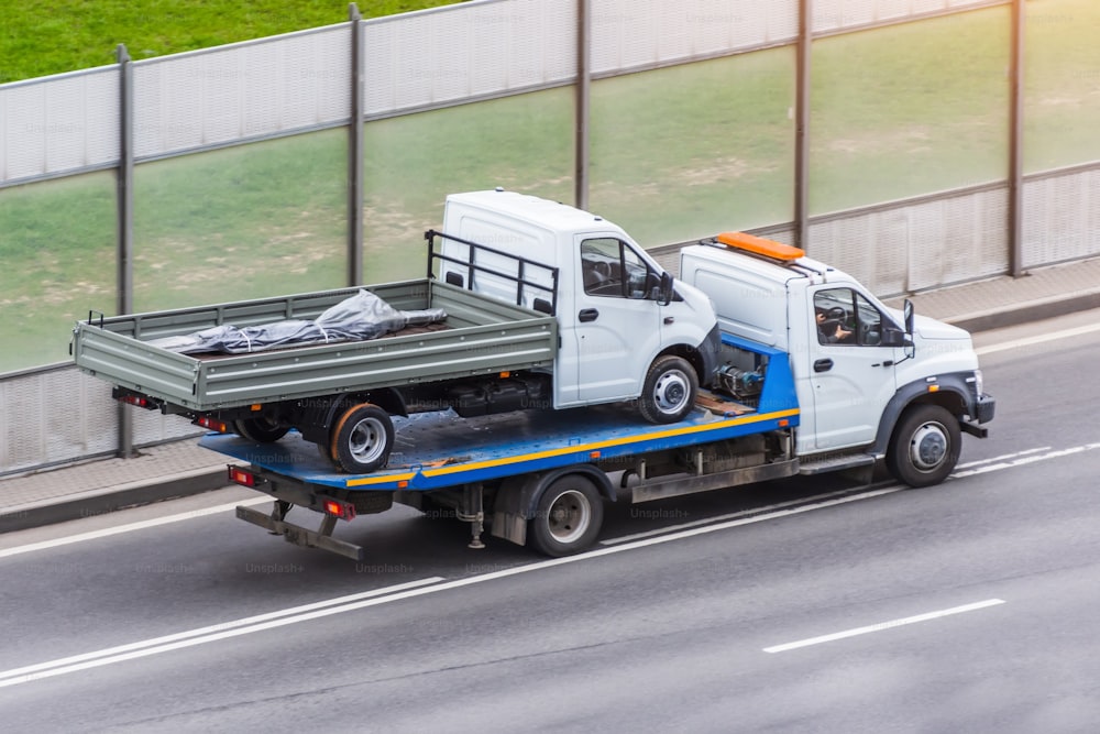 A truck is transporting another small truck on the road