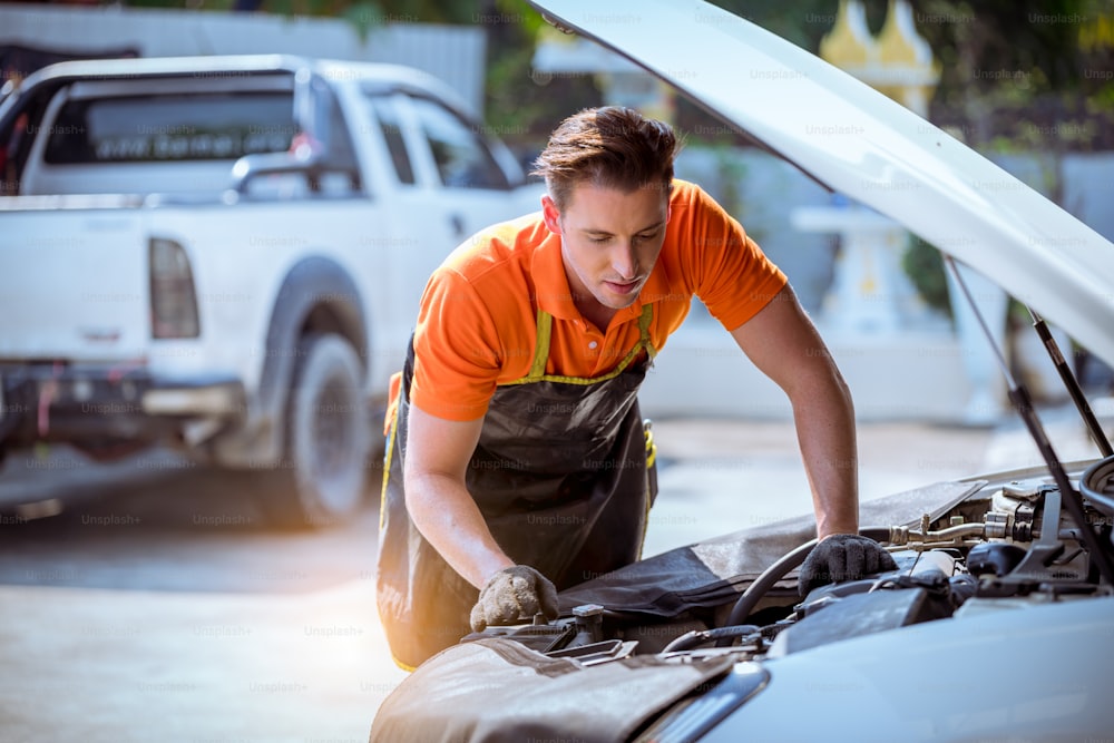 Mecânico de carro aberto sistema de reparos de capô de carro verificando o nível do motor de óleo para recarga e limpeza no serviço de garagem do carro.