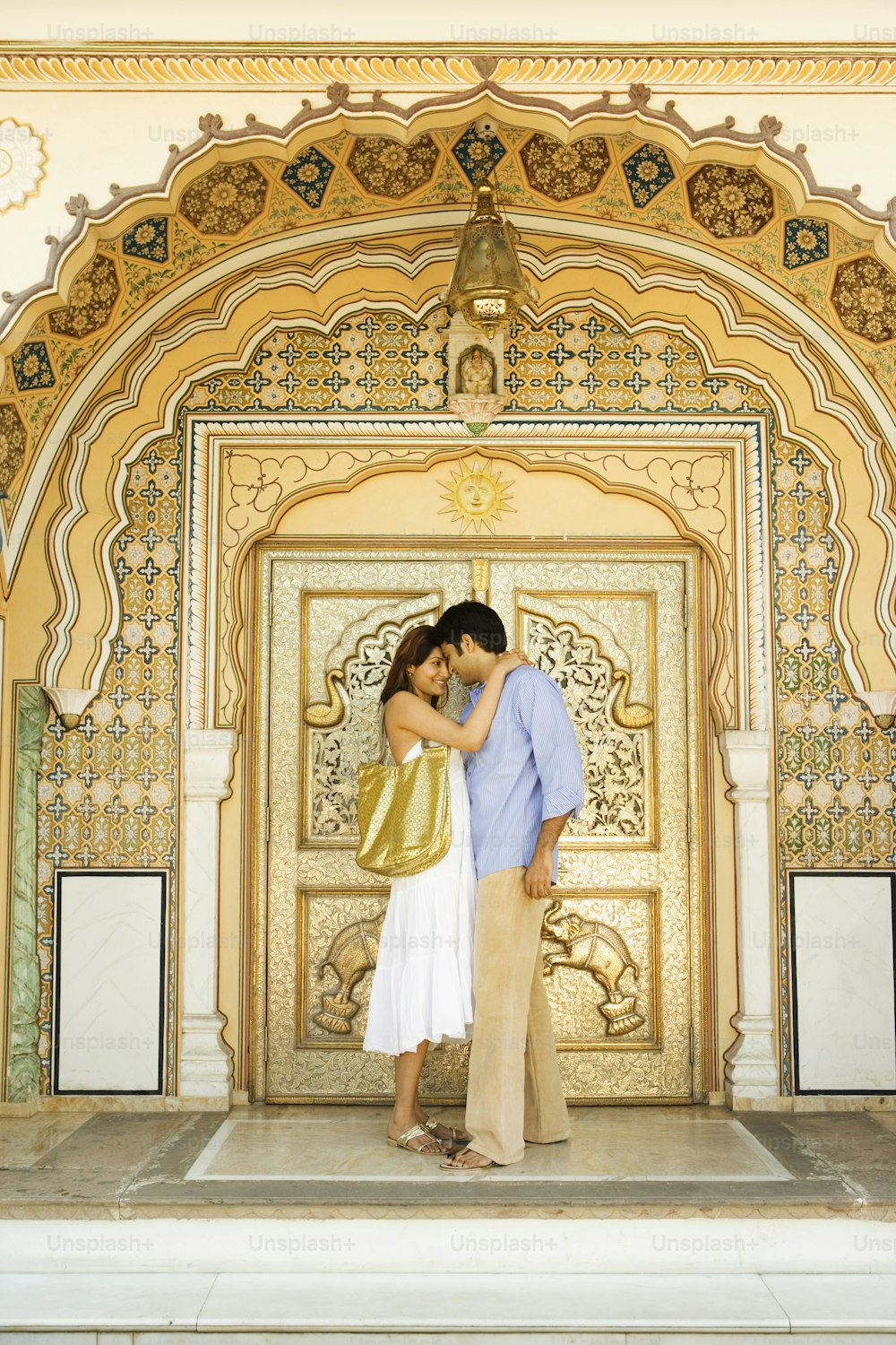 um casal se beijando em frente a uma porta dourada