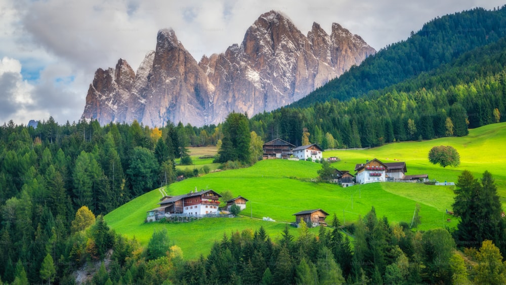 Villaggio di montagna in Val di Funes con scenario del Gruppo delle Odle nel Parco Naturale Puez-Odle, le Dolomiti nord-occidentali, Alto Adige, Italia settentrionale.