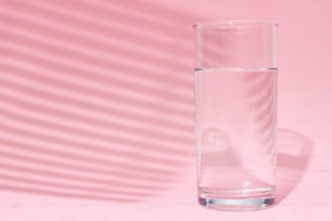 ピンクの背景にコップ一杯の水
