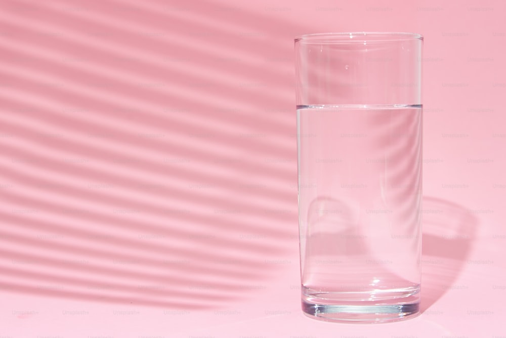 Vaso de agua sobre fondo rosa