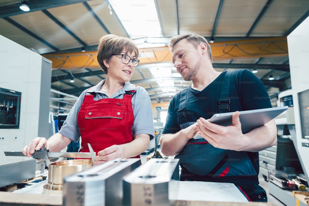 Man and women worker in the metalworking industry with workpieces