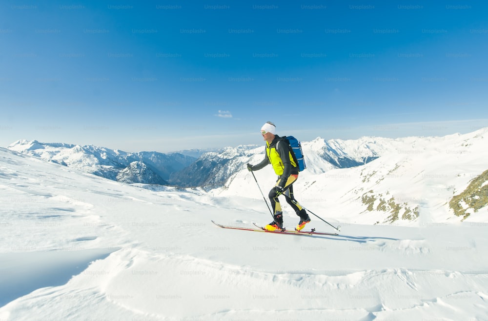 Um alpinista de esqui solo sobe com peles de foca sob seus esquis