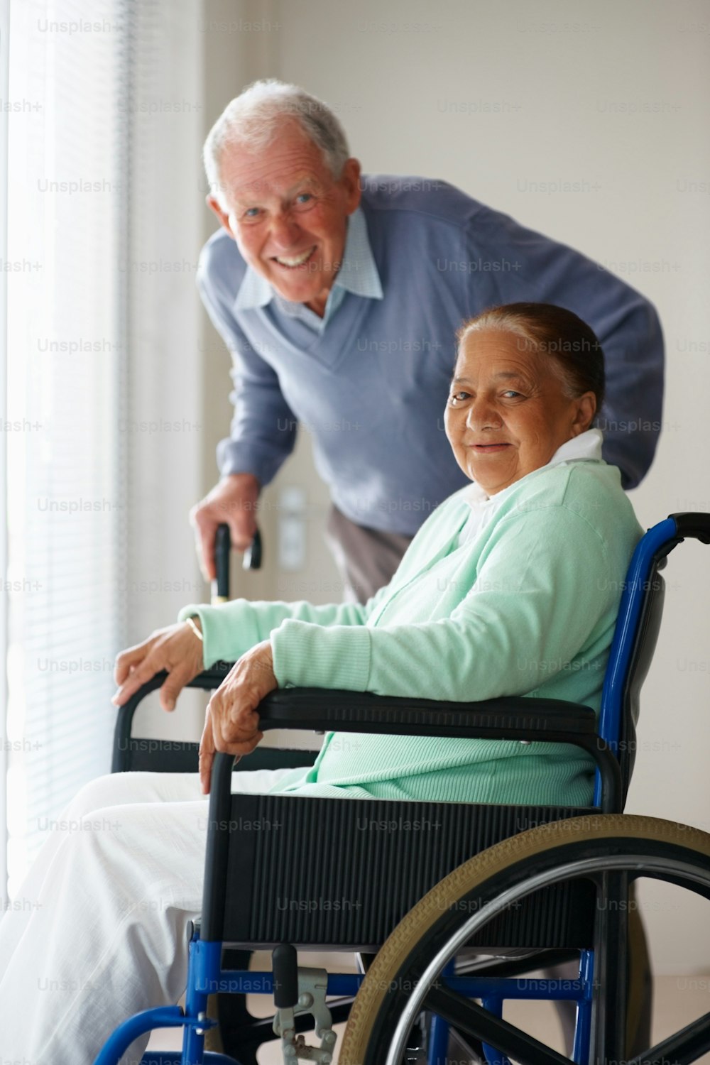 Hombre mayor feliz con esposa sentada en silla de ruedas