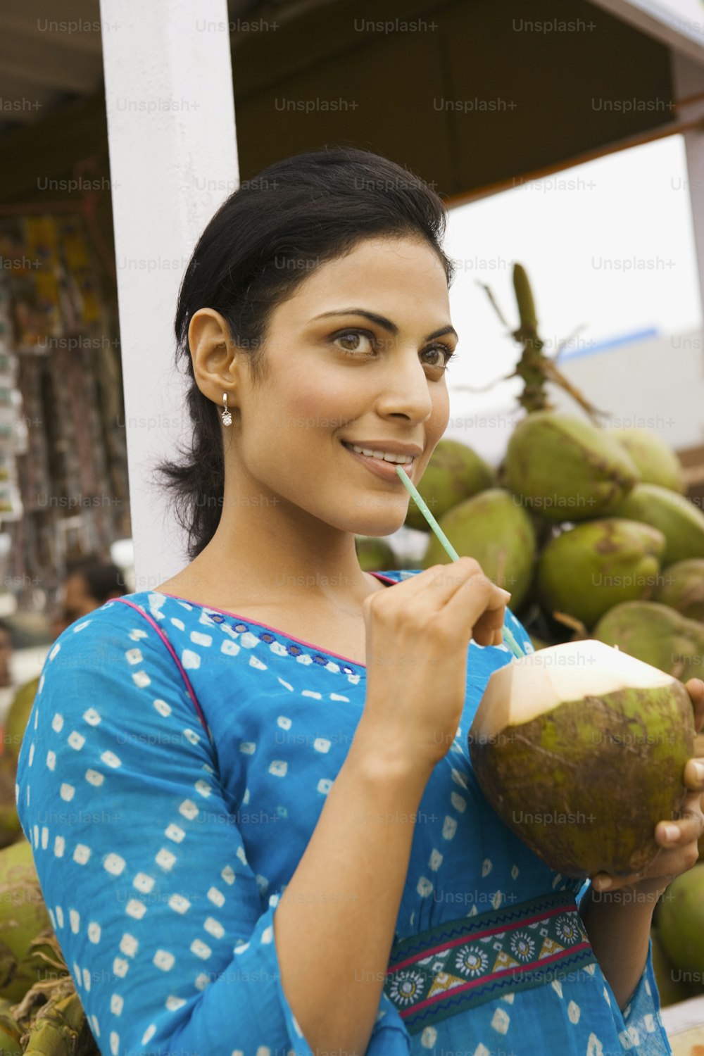 a woman holding a coconut and drinking a drink