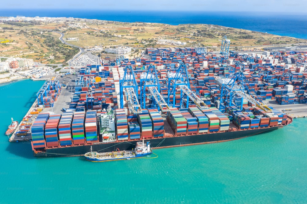 Huge ship with a large number of containers, moored to the port, cranes unload cargo. Great port, maritime transport, maritime traffic delivery concept
