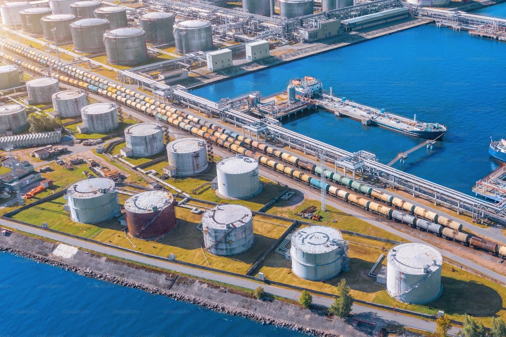 Vista aérea de la gran terminal portuaria de carga de petróleo con grandes tanques de almacenamiento. Infraestructura ferroviaria para la entrega de carga a granel por vía marítima, utilizando estación de bombeo en buque cisterna para el transporte y entrega