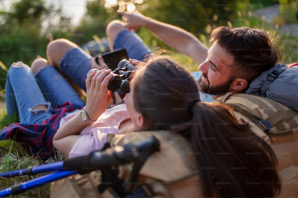 Couple resting after hiking in nature, they have fun with each other. People, love, nature and lifestyle concept.