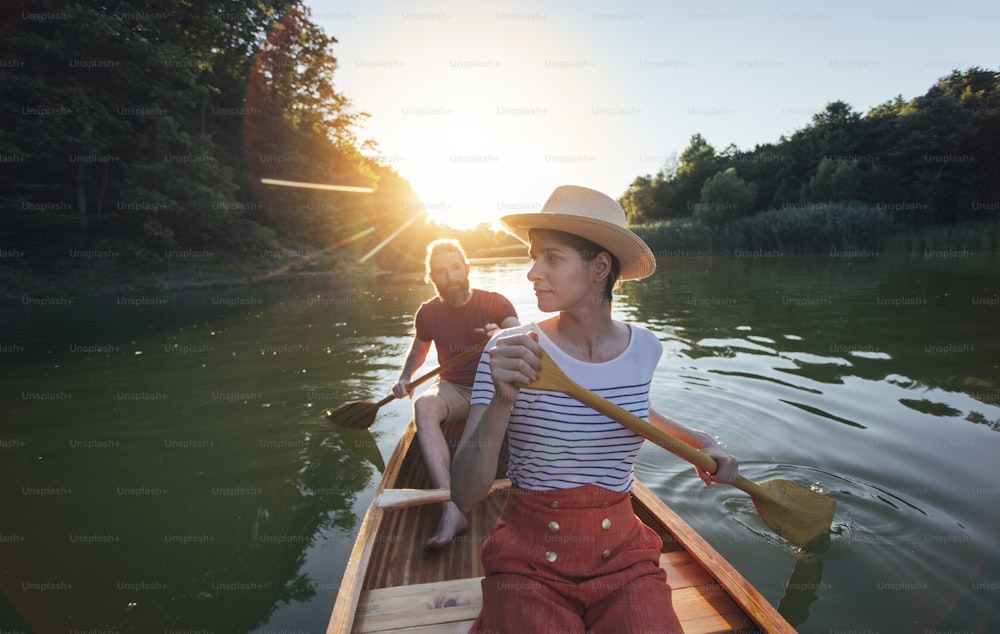 Le couple aime pagayer en canoë sur le lac au coucher du soleil. Femme et homme lors d’une promenade en bateau.
