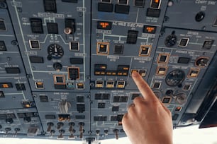 Flugzeugkapitän drückt den Schalter am Bedienfeld für die Scheibenheizung mit dem Finger während des Fluges