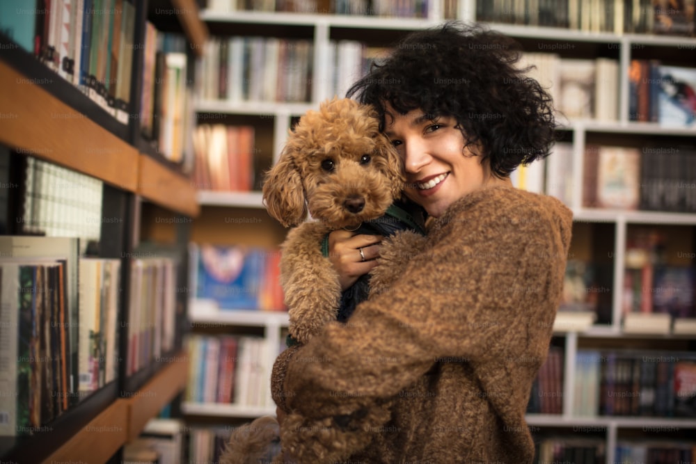 Mujer feliz con su perro en la biblioteca.