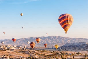 Muitos balões de ar quente voando sobre a paisagem rochosa na cidade de Goreme na Capadócia, Turquia