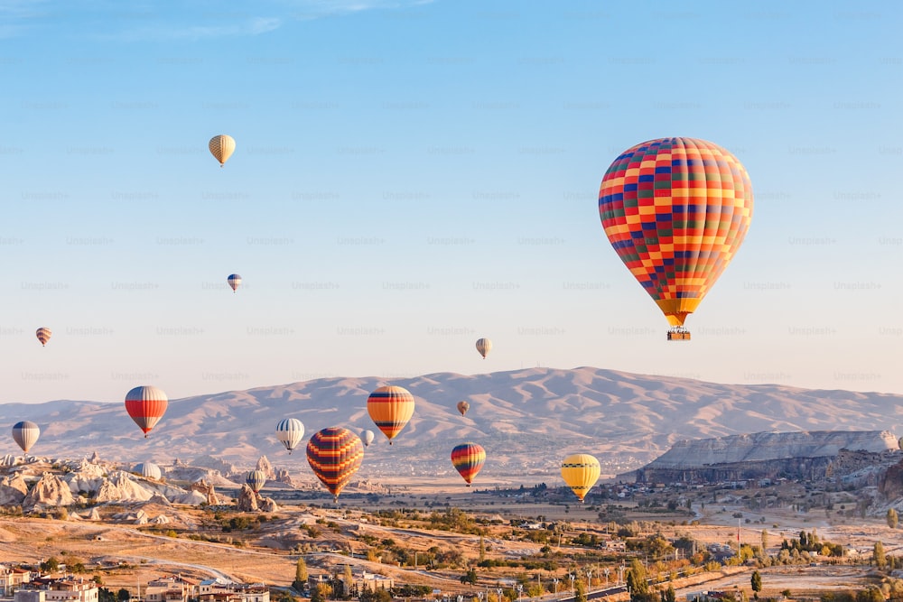 Many Hot air balloons flying over rocky landscape in Goreme city at Cappadocia, Turkey