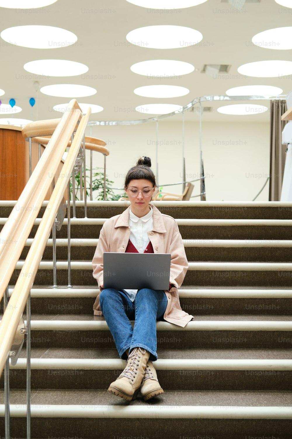 Young woman sitting on stairs and using laptop for study