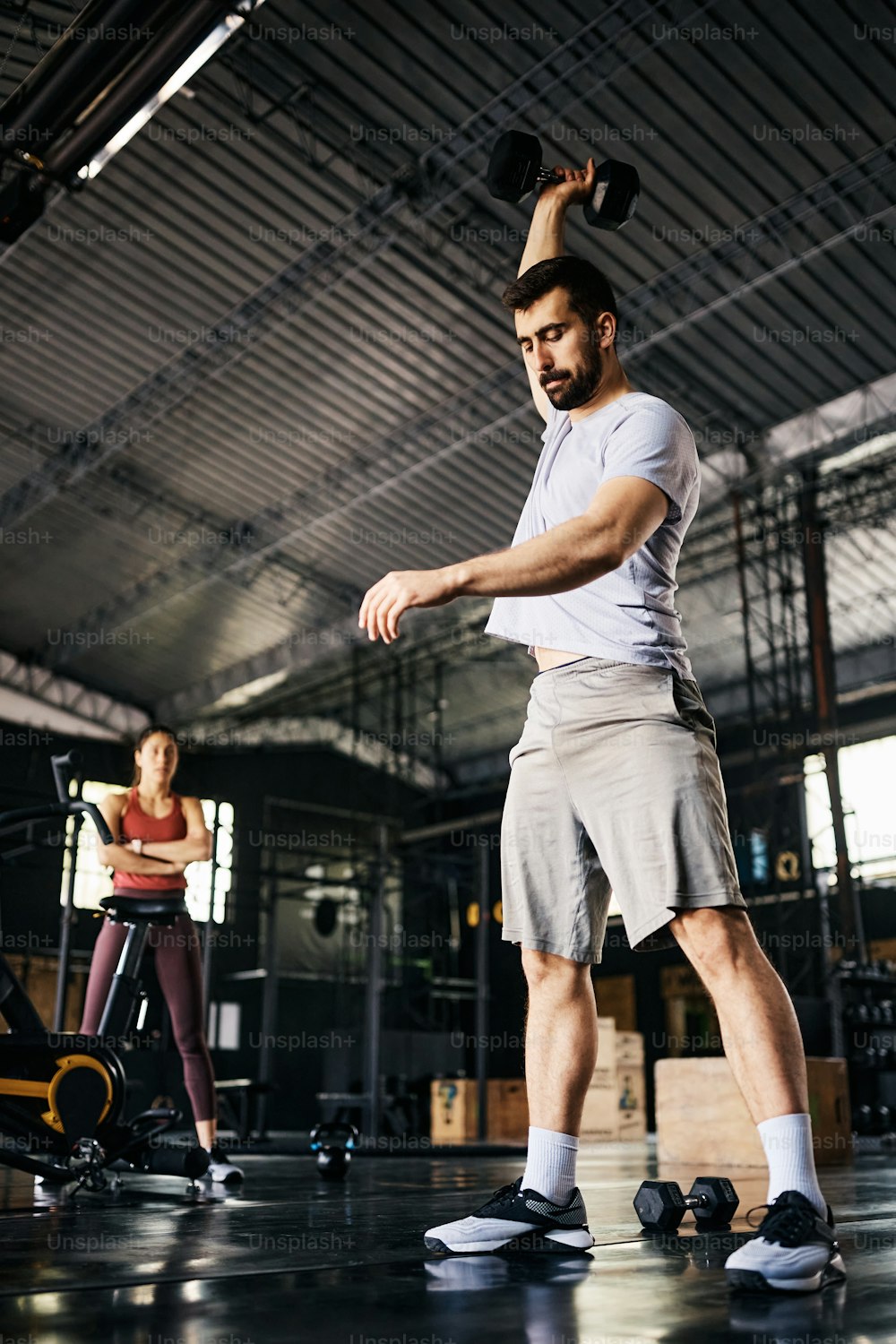 Visão de baixo ângulo do homem atlético usando o peso da mão enquanto se exercita em uma academia.