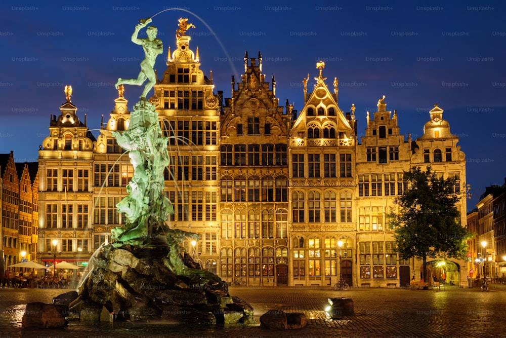 アントワープの有名なブラボー像とマルクト広場の噴水は、夜に照らされ、古い家々。ベルギー、アントワープ