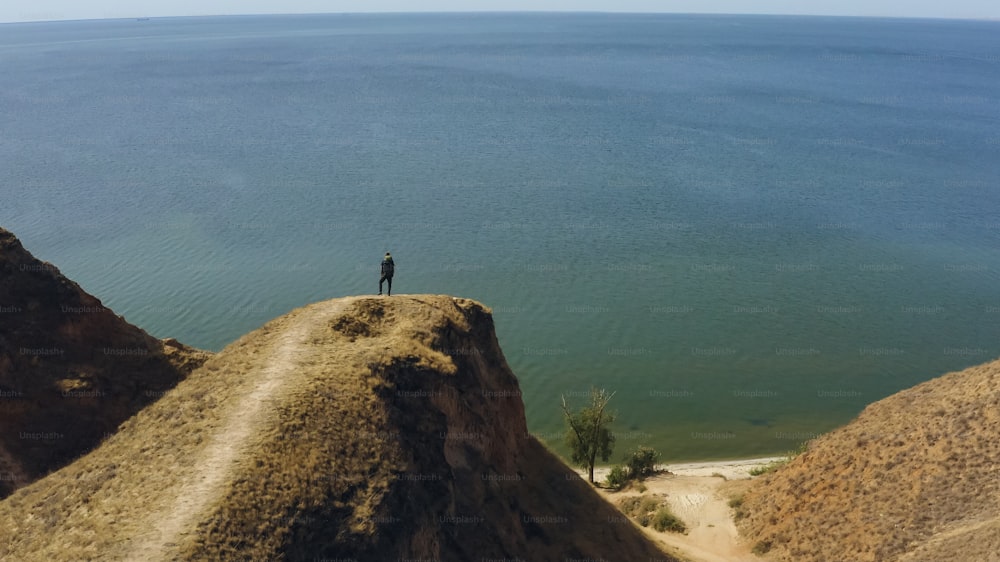 O turista em pé no penhasco da montanha perto do mar