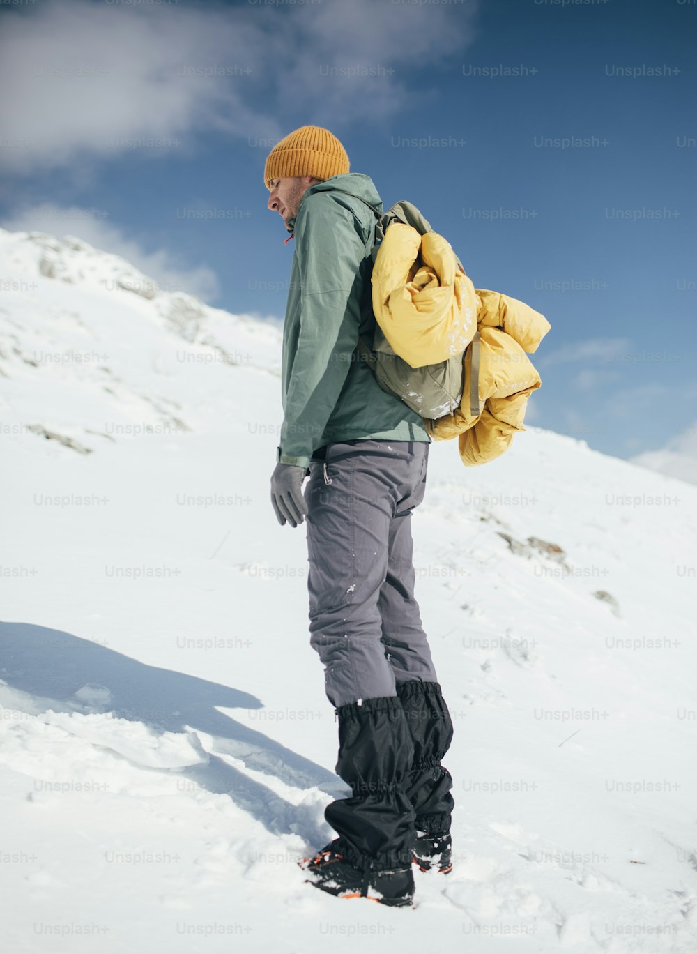 Mountaineer with gaiters and backpack posing.