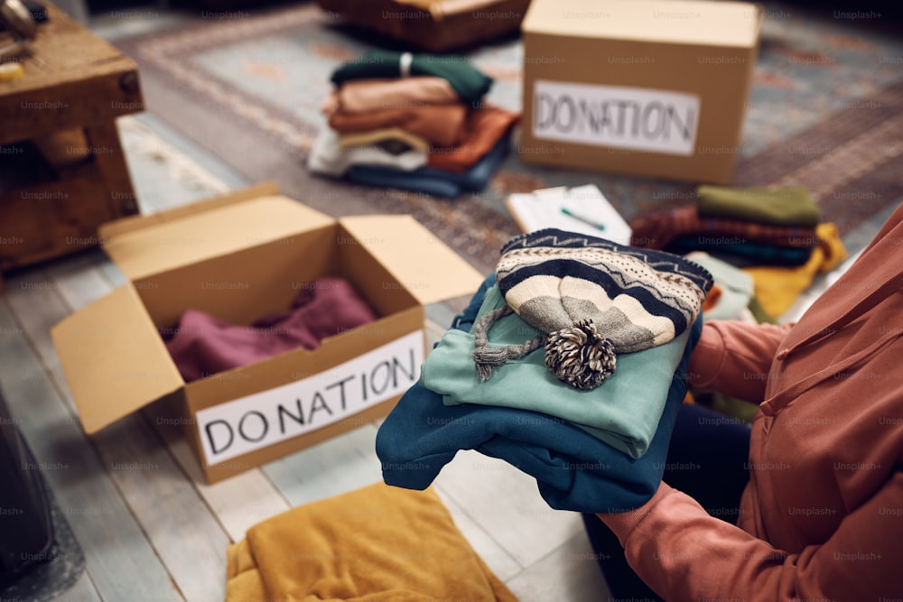 Close-up of woman packing boxes while donating her wardrobe for charity.