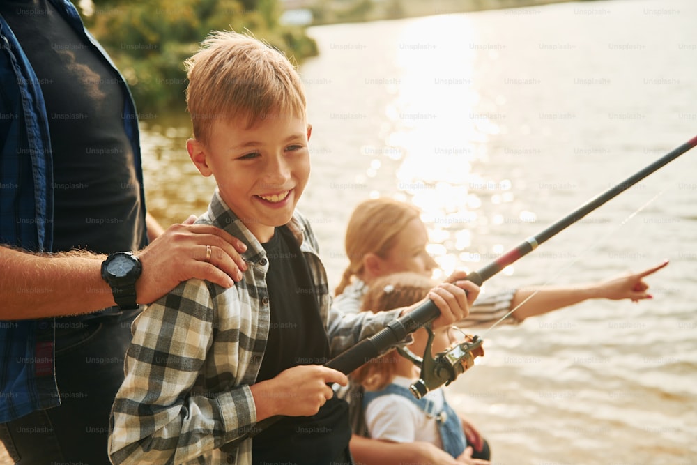 Imparare a pescare. Padre e madre con figlio e figlia insieme all'aperto in estate.