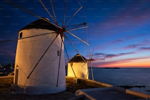 Malerische Aussicht auf die berühmten Windmühlen der Stadt Mykonos Chora. Traditionelle griechische Windmühlen auf der Insel Mykonos, die abends beleuchtet werden, Kykladen, Griechenland. Gehen mit Steadycam.