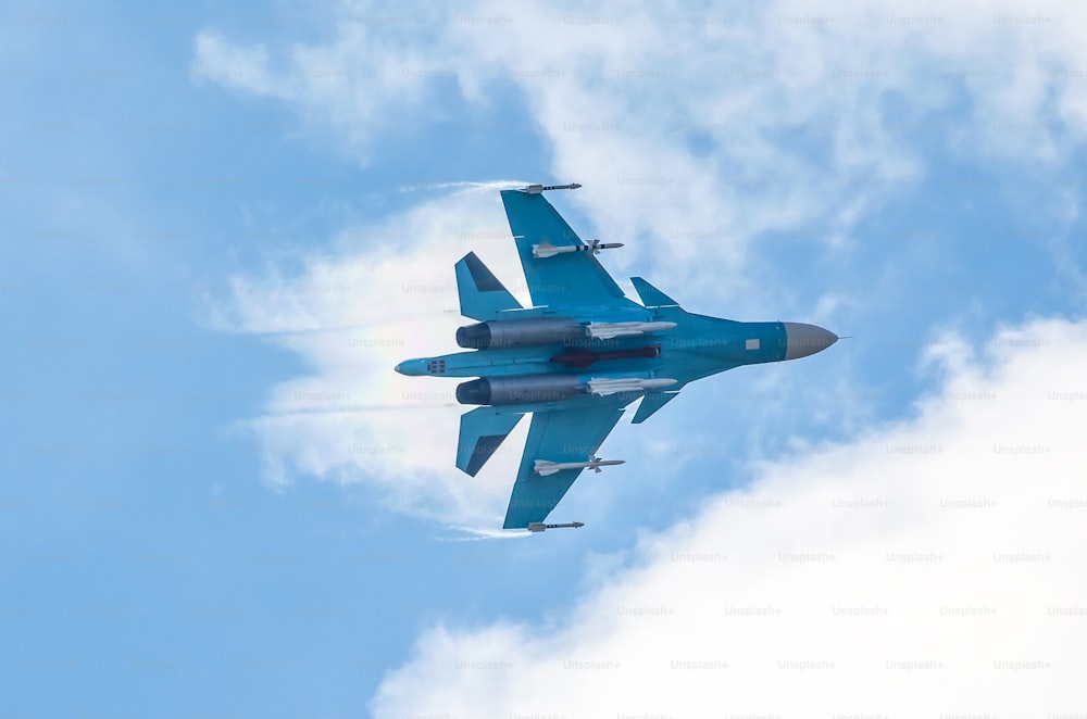 Combat fighter flies performing a maneuver in the air with a trail of a pair of clouds