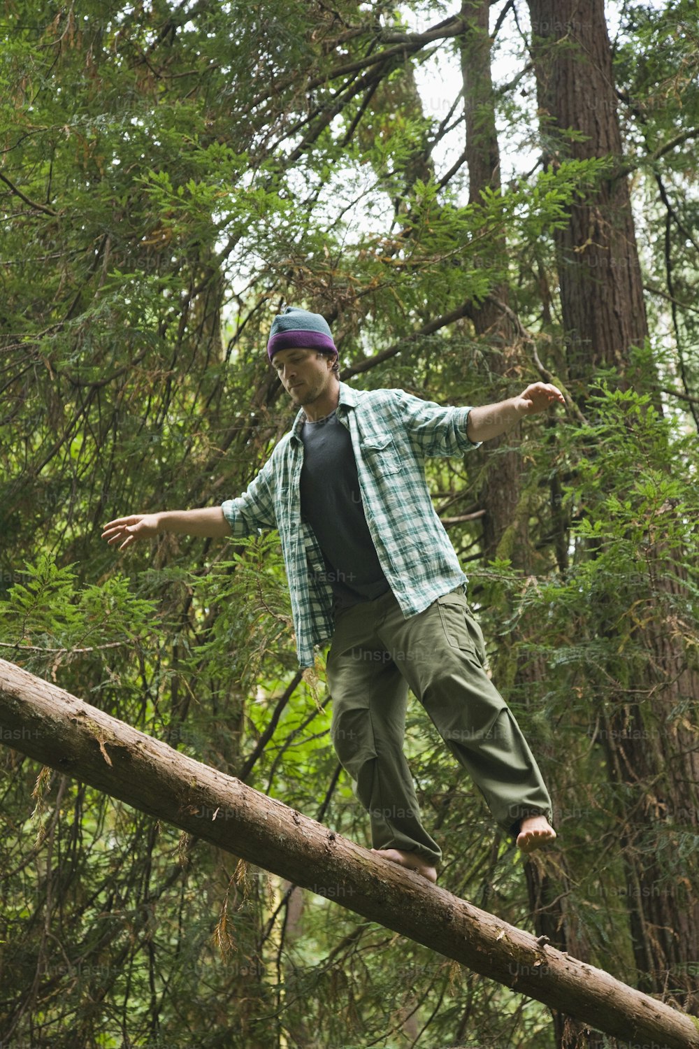 한 남자가 숲 속의 통나무 위에서 균형을 잡고 있다