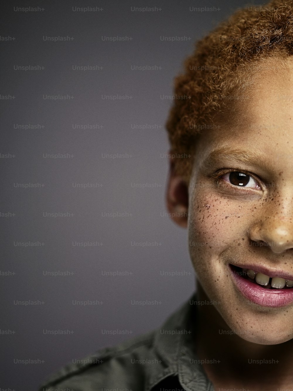 a young boy with freckled hair smiling at the camera