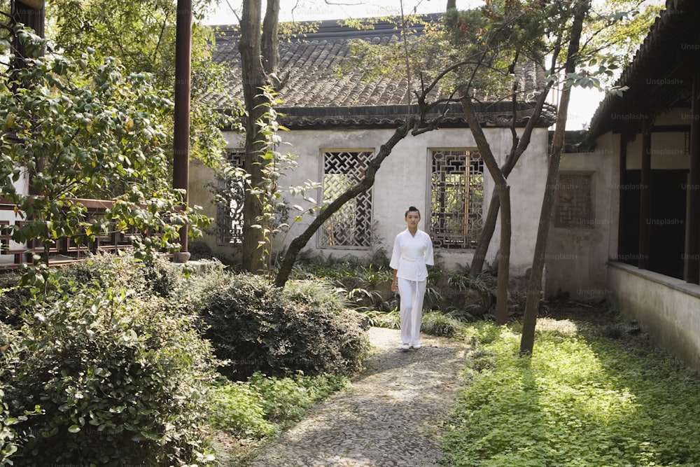 a man in white walking down a path in front of a building