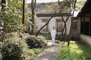 a man in white walking down a path in front of a building