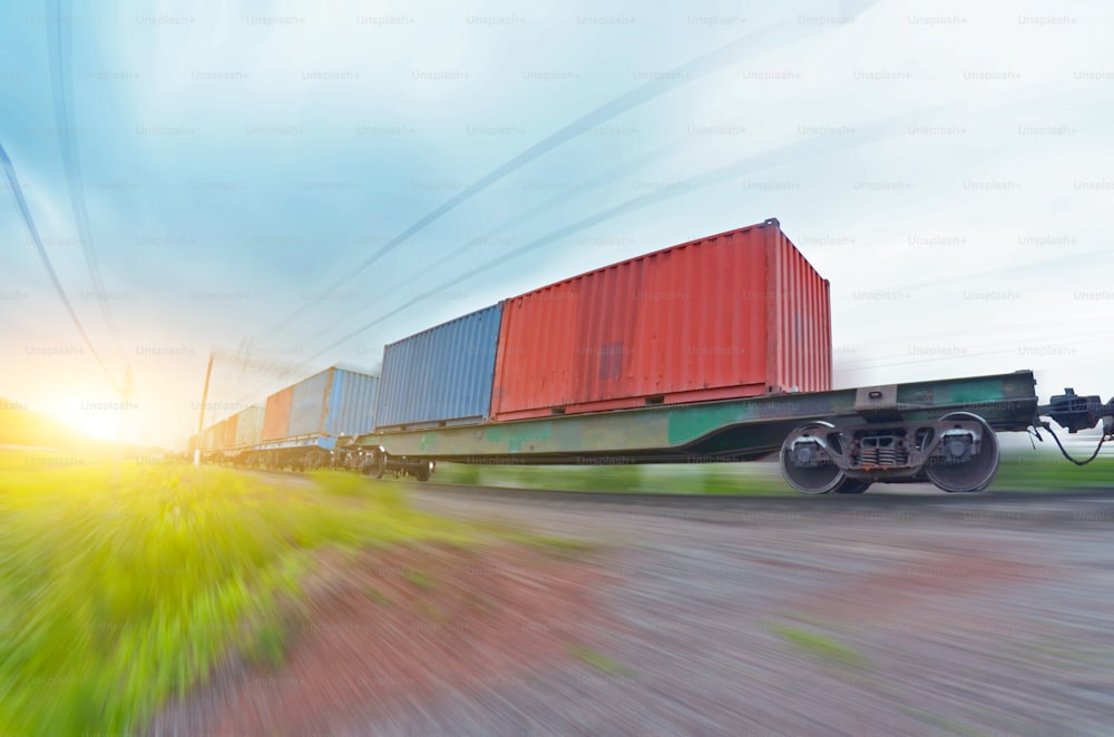 Freight train rides at speed with container and cargo at sunset