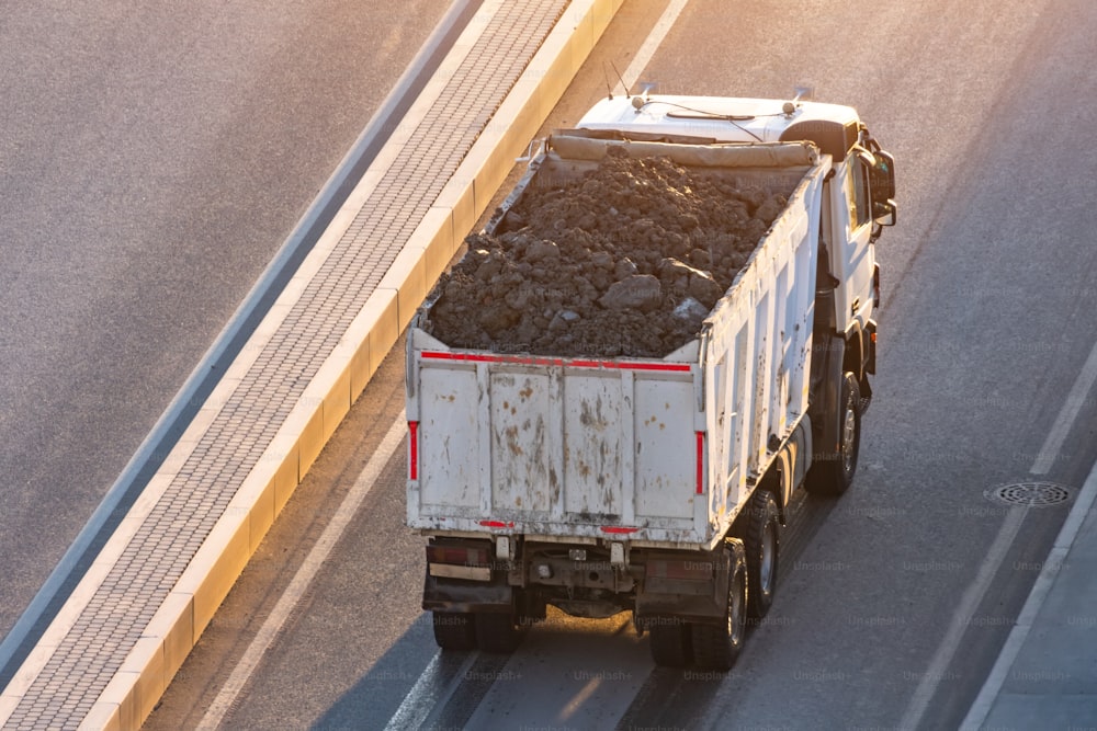 Truck loaded with soil in the back is on the side of the highway