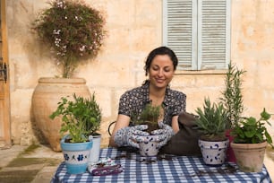 a woman sitting at a table with potted plants