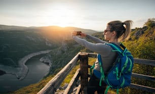 Junge Wanderin fotografiert mit Smartphone vom Aussichtspunkt des Canyons.