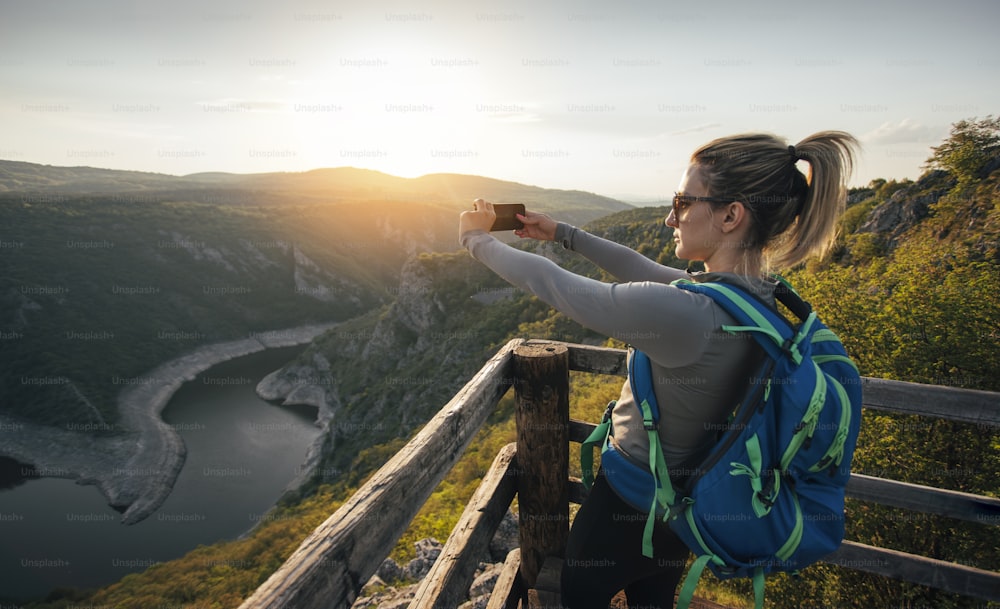 Giovane escursionista donna che scatta foto con smartphone dal punto di vista del canyon.