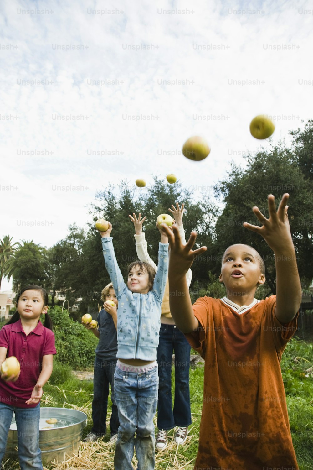 Un groupe d’enfants jette des pommes en l’air