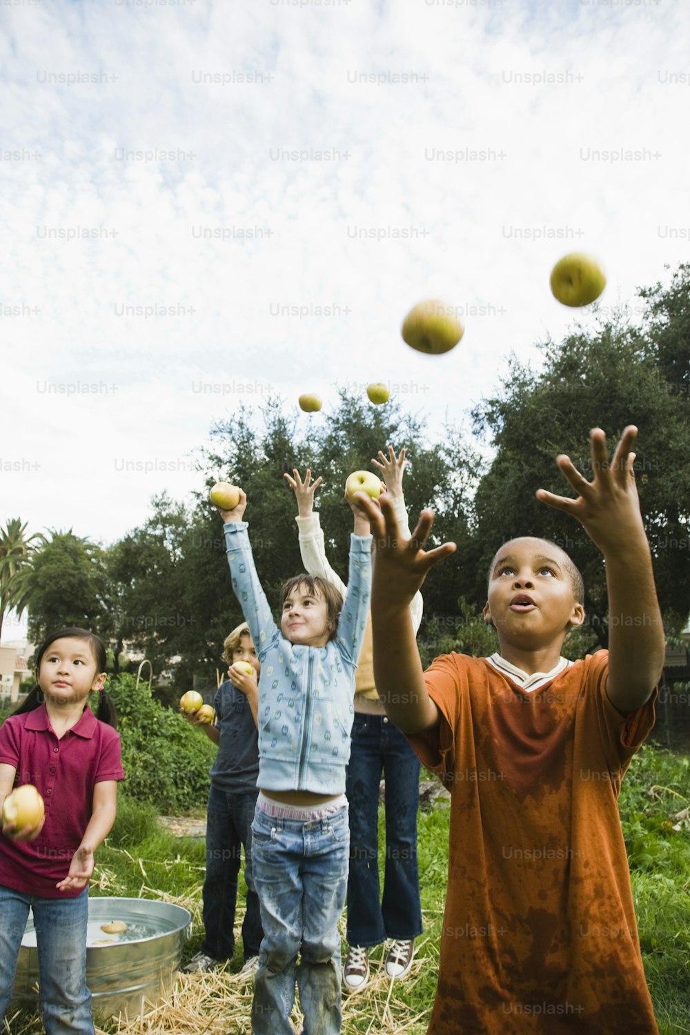 a group of children are throwing apples in the air
