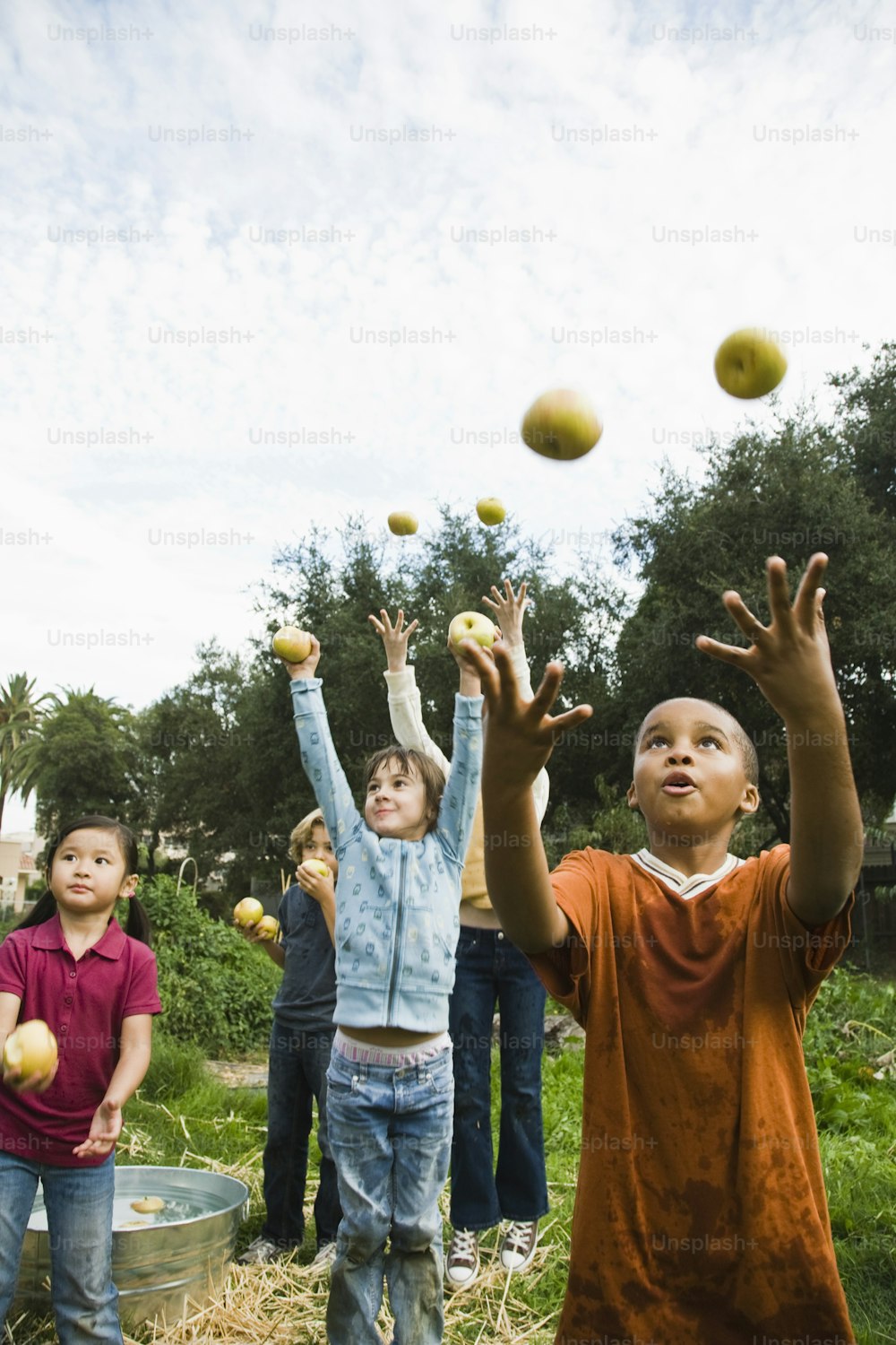 Un grupo de niños lanza manzanas al aire