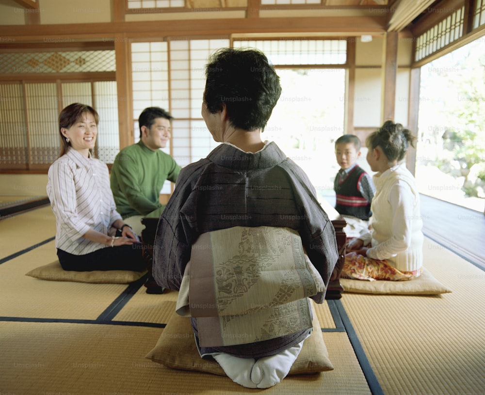 Three generation family kneeling on cushions at table, talking