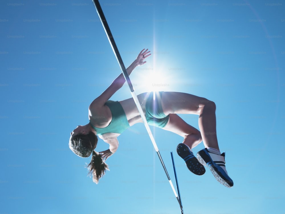 a woman is high in the air on a pole
