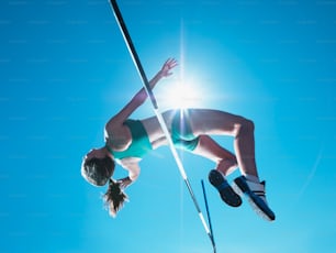 a woman is high in the air on a pole