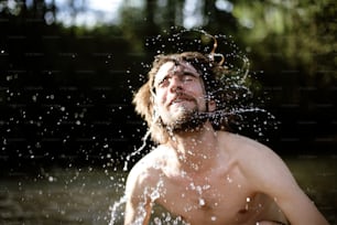 a shirtless man splashing water on his face