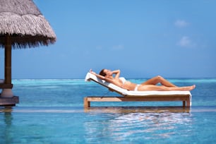 a woman laying on a chaise lounge in the ocean