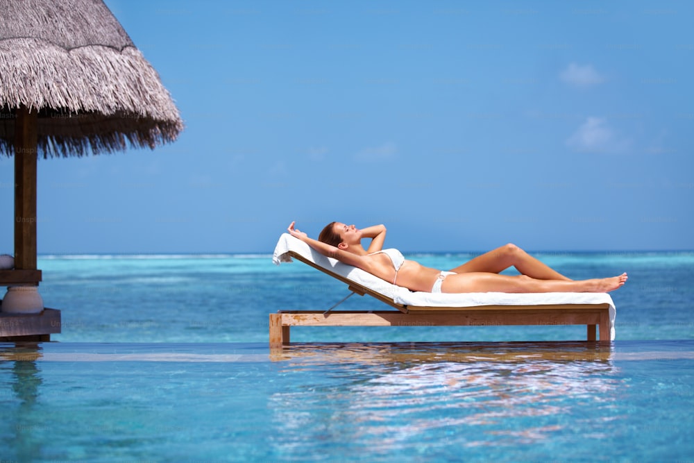 a woman laying on a chaise lounge in the ocean
