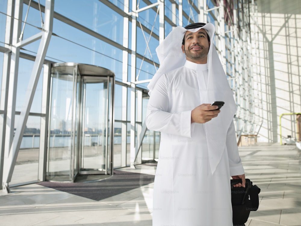 a man in a white outfit holding a cell phone