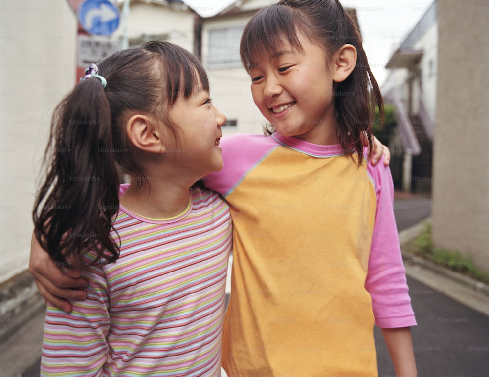 Two girls (6-9) walking with arms around one another, smiling