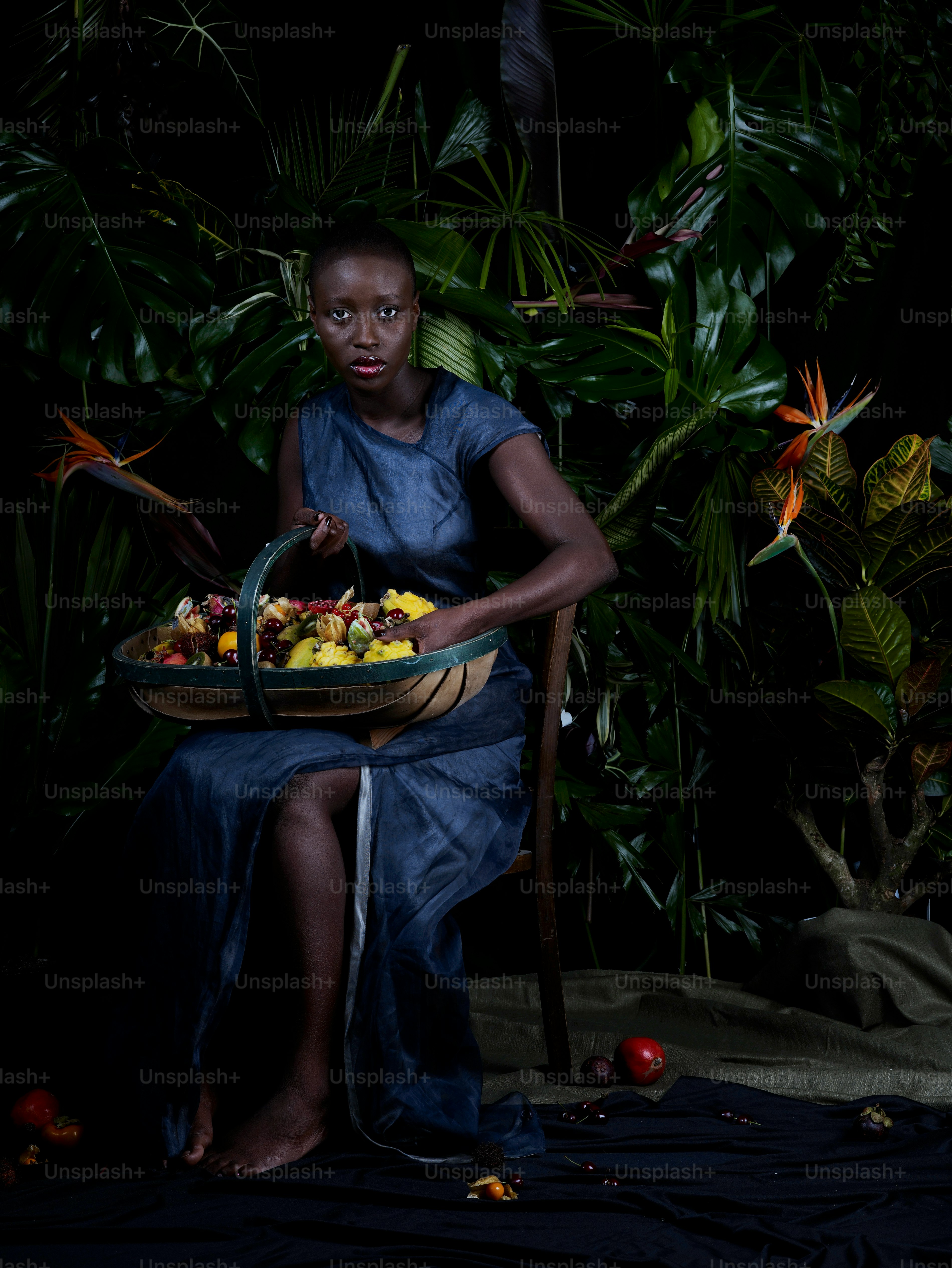 a woman sitting in a chair holding a basket of fruit